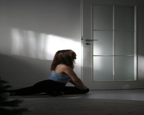 A resident elegantly doing light stretches at home with soft morning window light