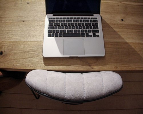 A well-arranged modern desk environment featuring an aligned laptop stand and structured supporting pillow